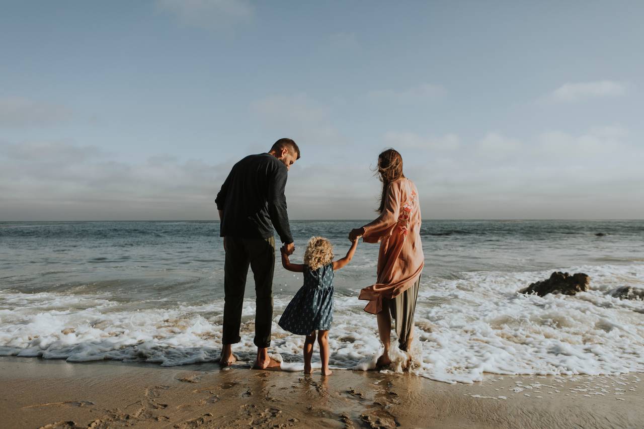 Rodzice razem z dzieckiem stoją na brzegiem morza