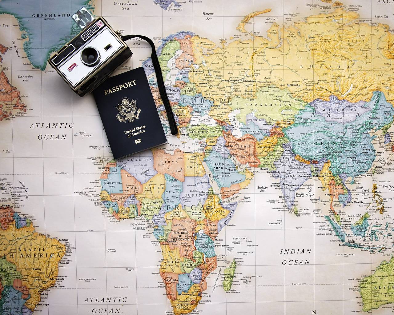 Paszport i stary aparat fotograficzny leżą na mapie świata
