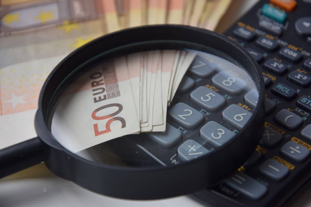 Lupa, pieniądze i kalkulator jako symbole analizy swoich finansów i zasad oszczędzania