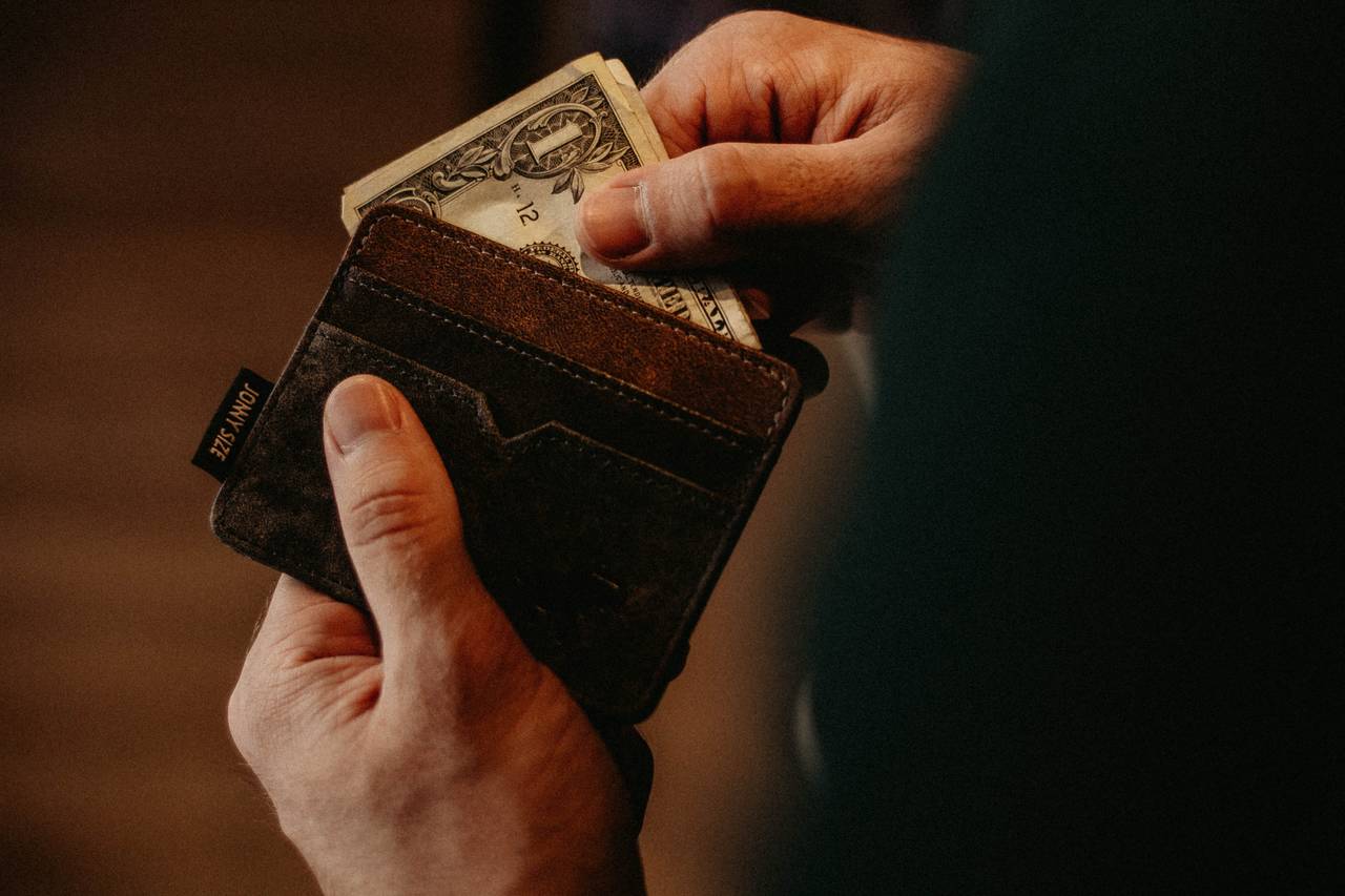 Mężczyzna wyciąga pieniądze z portfela stosując zasady racjonalnego wydawania pieniędzy