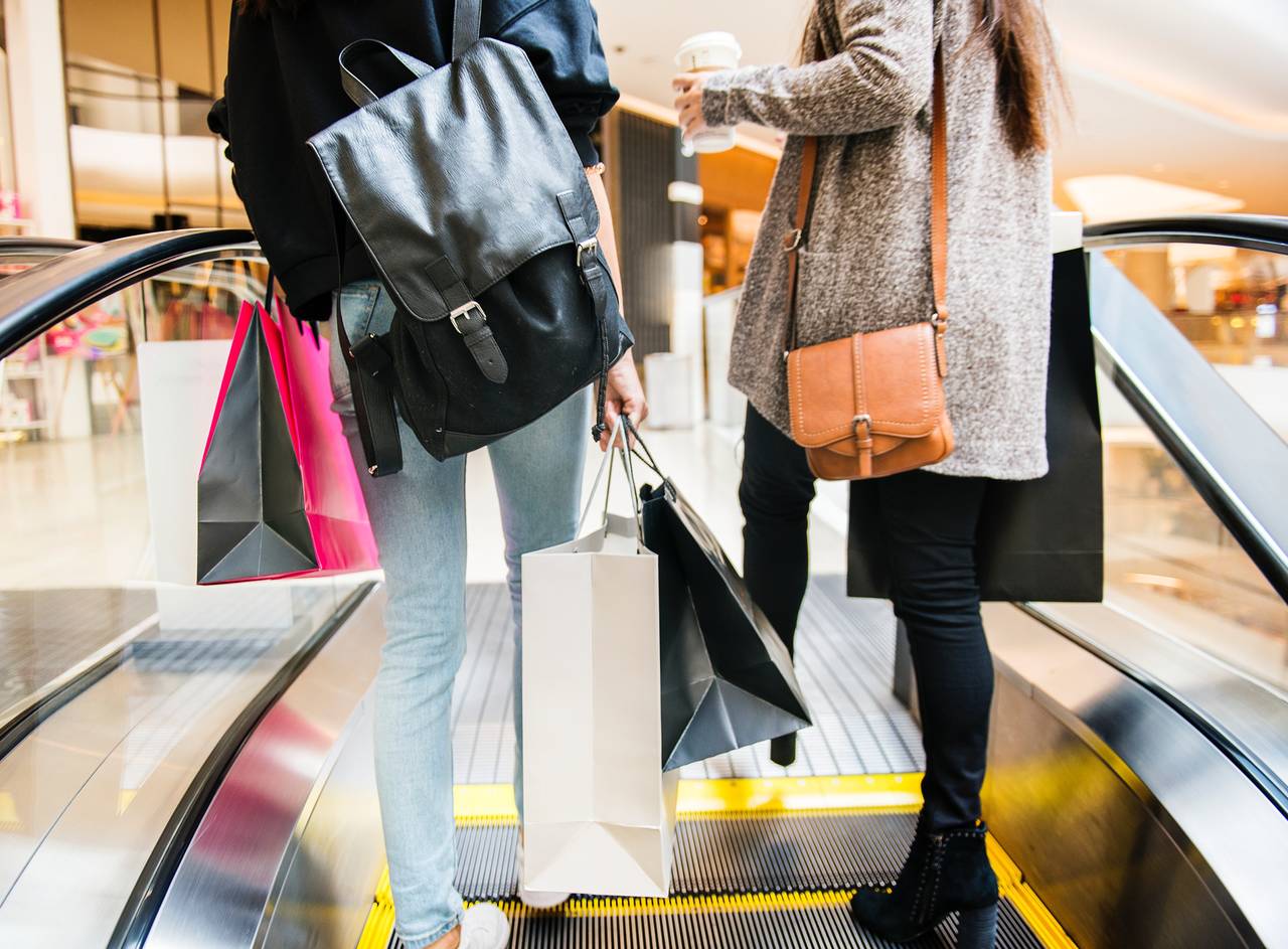 Dwie osoby jadące po ruchomych schodach w centrum handlowym jako symbole błędów finansowych związanych ze zbyt dużymi wydatkami