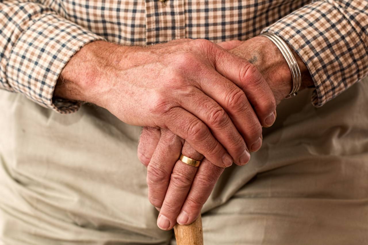 Dłonie starszego mężczyzny jako symbol noworocznego postanowienia finansowego związanego z odkładaniem na emeryturę