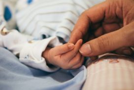 Rodzic trzyma swoje dziecko za rękę jako symbol Formalności po urodzeniu dziecka, które trzeba spełnić