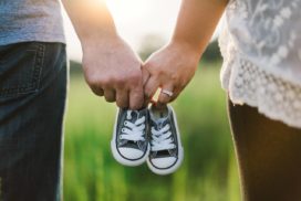 Para trzyma parę małych butów dziecięcych jako symbol przygotowań siebie i finansów domowych na narodziny dziecka